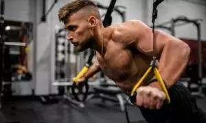 topless man in black pants holding black and yellow exercise equipment
